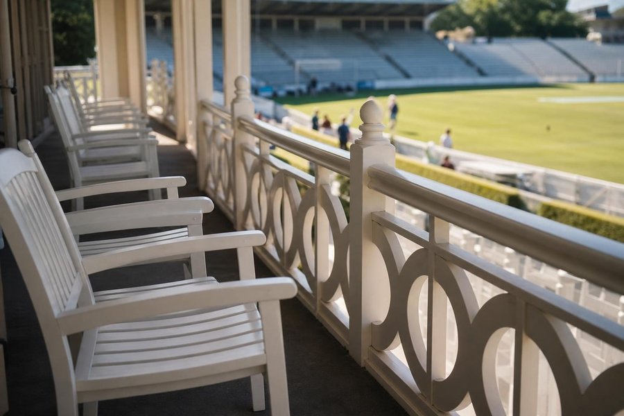 A pavilion balcony with empty white chairs in morning sun and a calm ground in the distance, a calendar-like sense of waiting for play. (AI-generated image)
